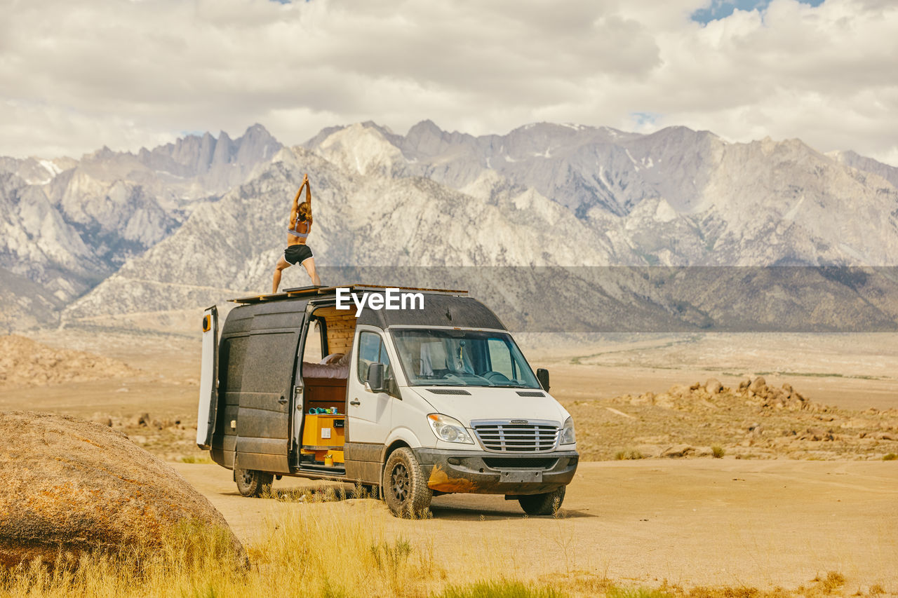 Woman practicing yoga on roof of camper van in northern california.