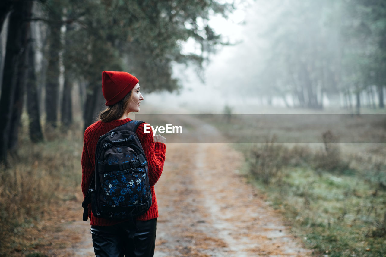 Weekend breaks and getaways in forests. stay close to nature. young woman in red hat and sweater