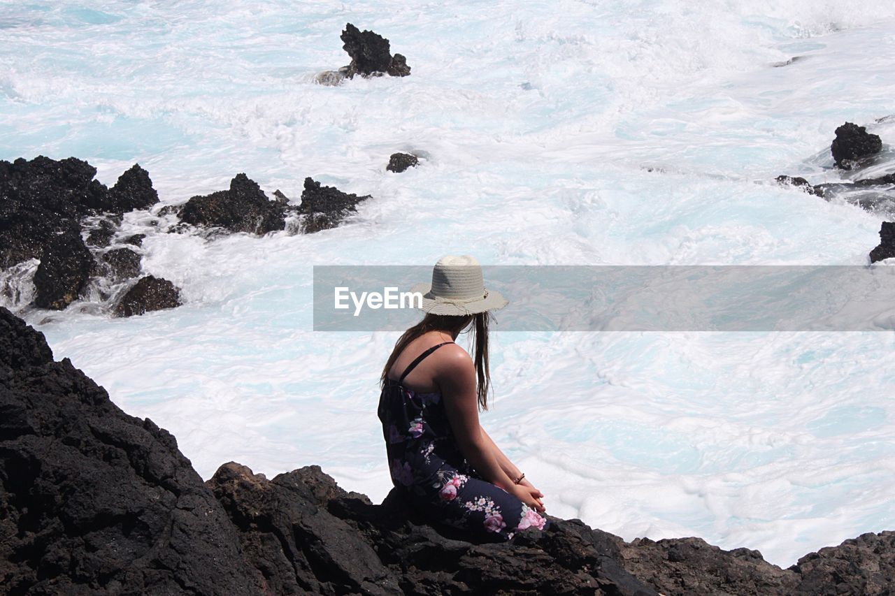 Woman relaxing by sea on rock