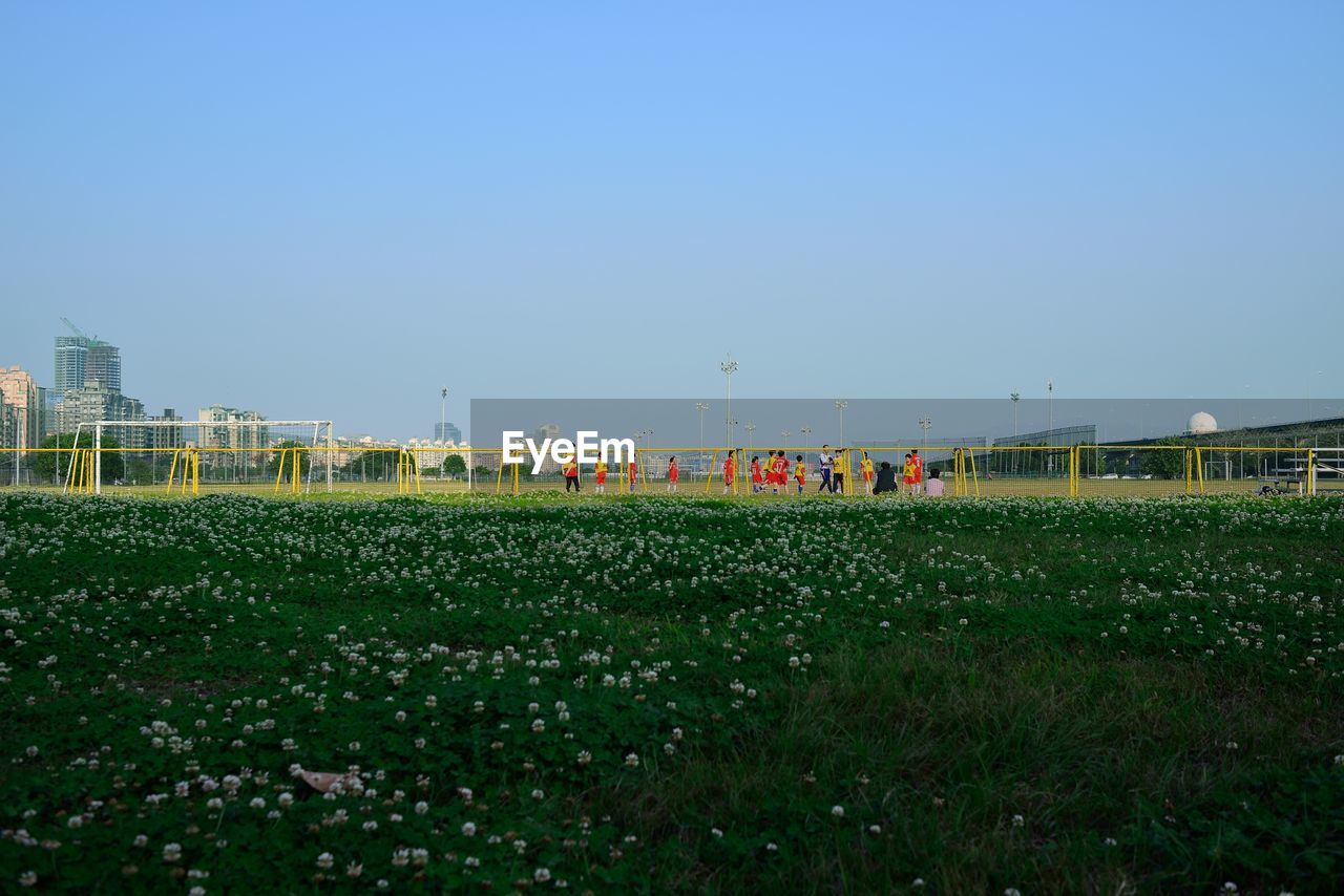 People on soccer field against clear sky