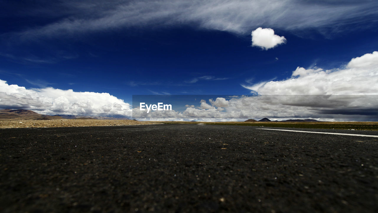 Road by landscape against blue sky