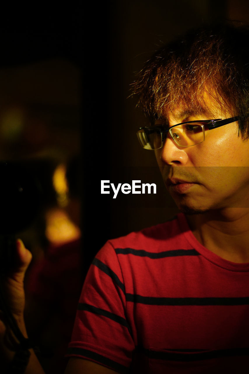 Close-up portrait of young man wearing eyeglasses at home