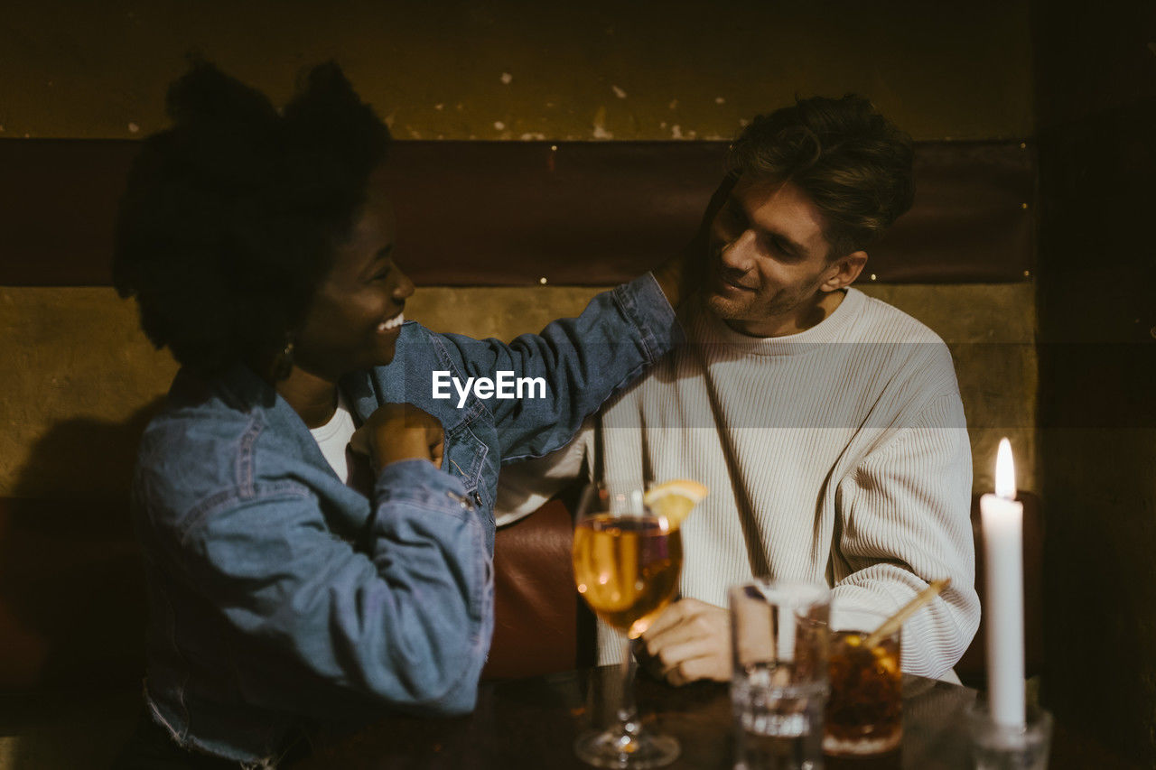 Romantic woman caressing boyfriend while sitting at restaurant