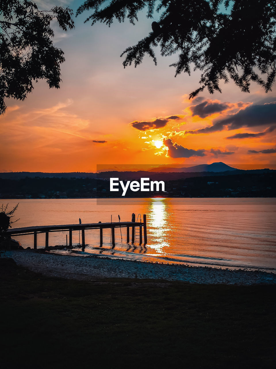 water, sky, sunset, sea, beauty in nature, beach, scenics - nature, nature, cloud, tranquility, land, tranquil scene, tree, silhouette, orange color, reflection, idyllic, travel destinations, holiday, dusk, outdoors, vacation, trip, evening, afterglow, sun, plant, environment, horizon over water, sunlight, travel, seascape, horizon, non-urban scene, landscape, no people, relaxation, ocean, coastline