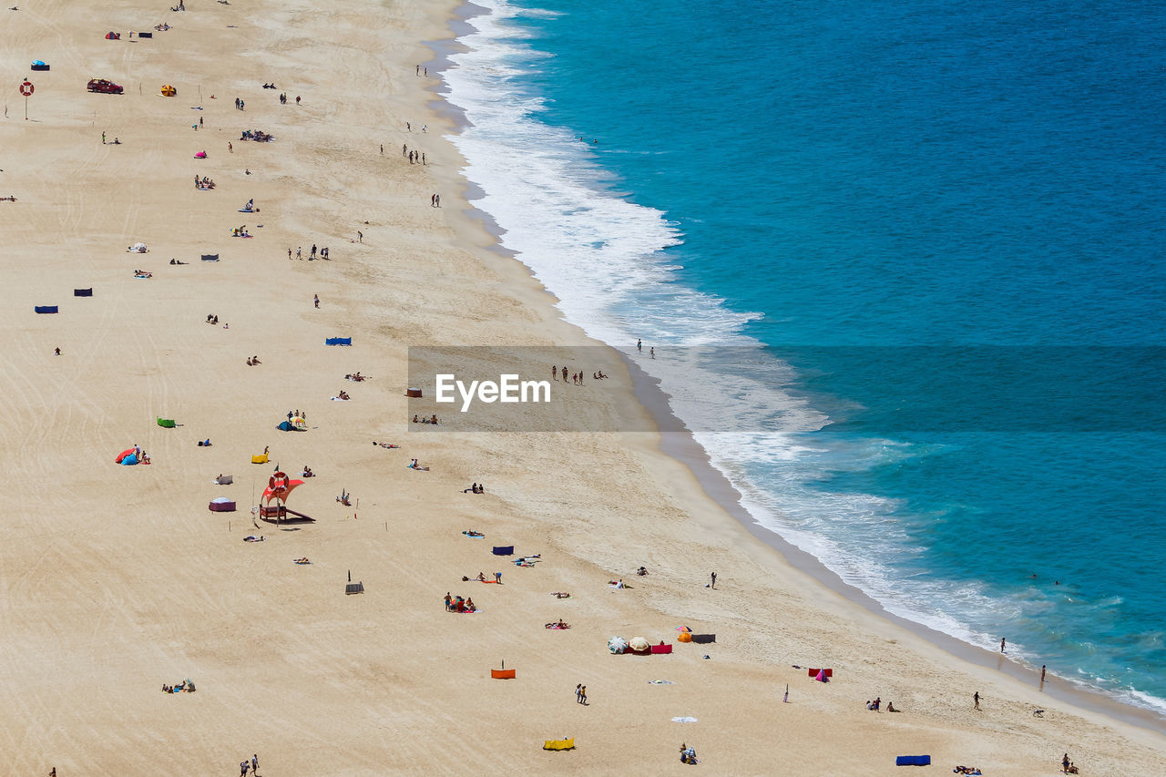 High angle view of people lying on beach with blue sea