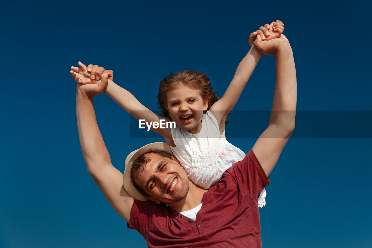 Portrait of smiling father and daughter against sky