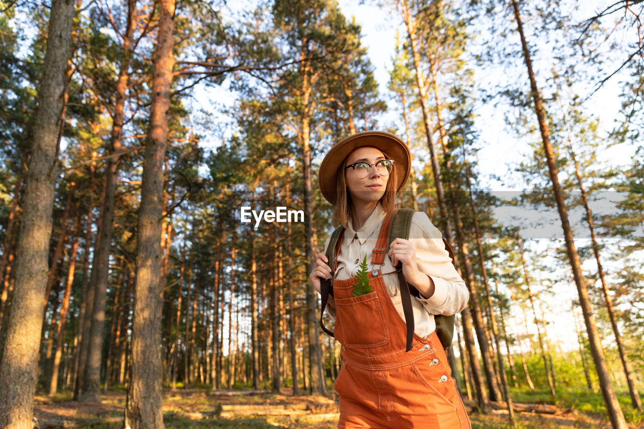 Woman botanist on ecological hiking trail in summer. naturalist exploring wildlife and ecotourism.