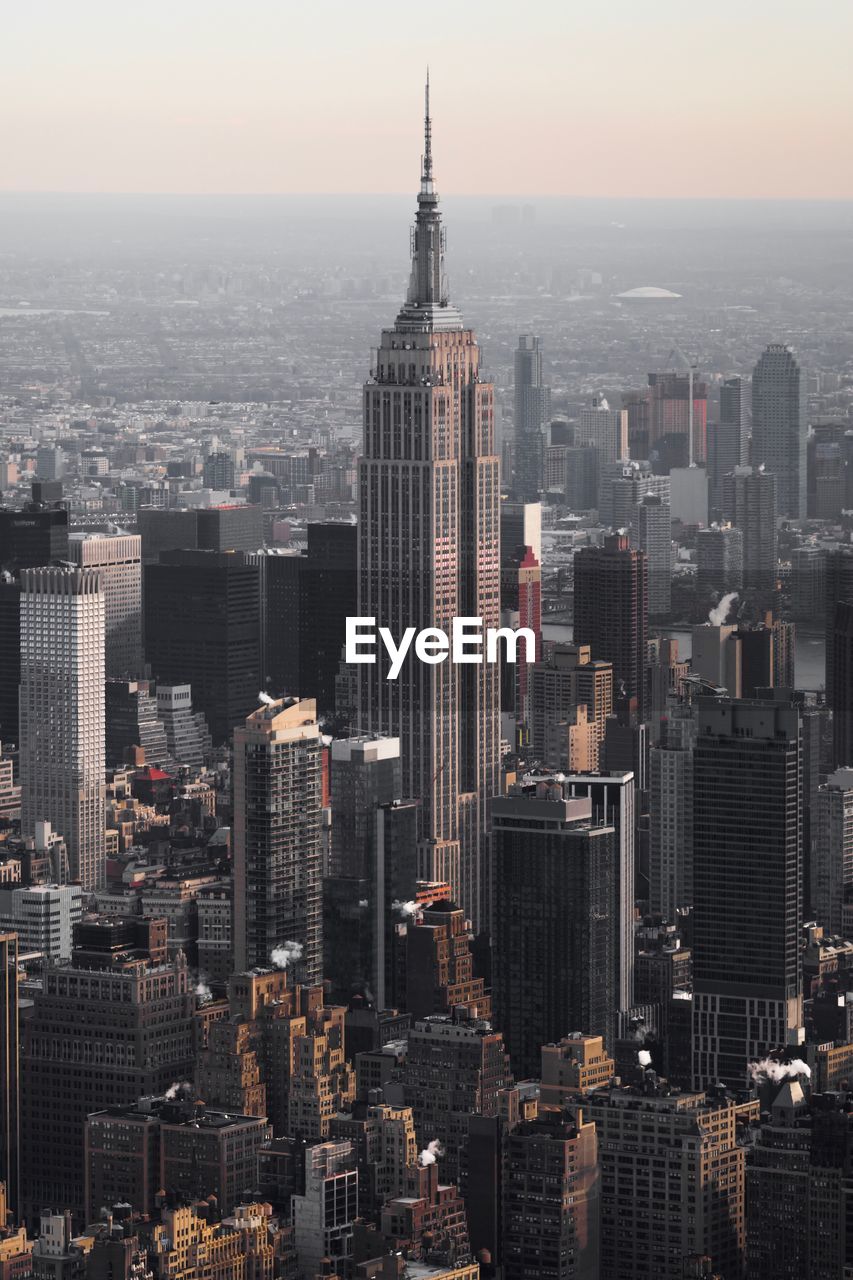 High angle view of empire state building in city during sunset