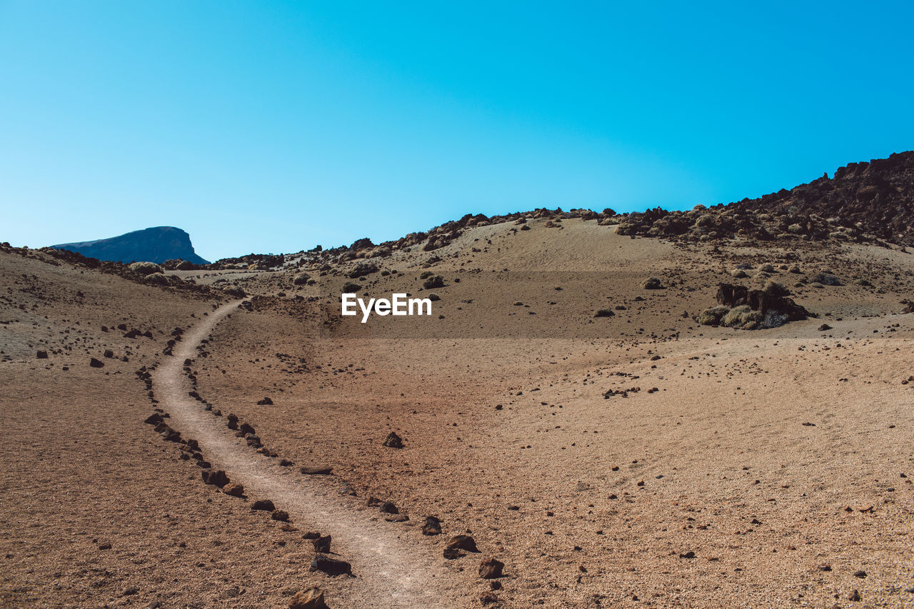 Scenic view of desert against clear blue sky