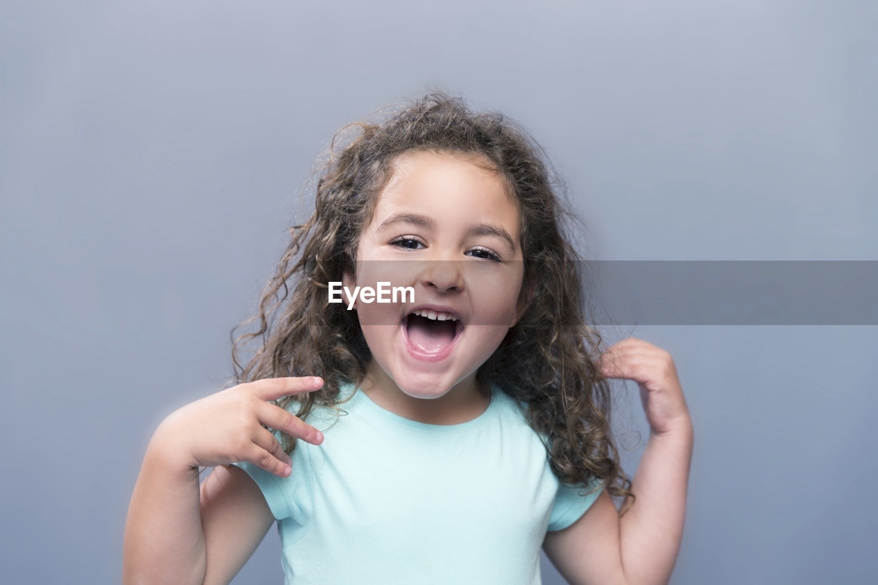 Portrait of cheerful girl standing against gray background