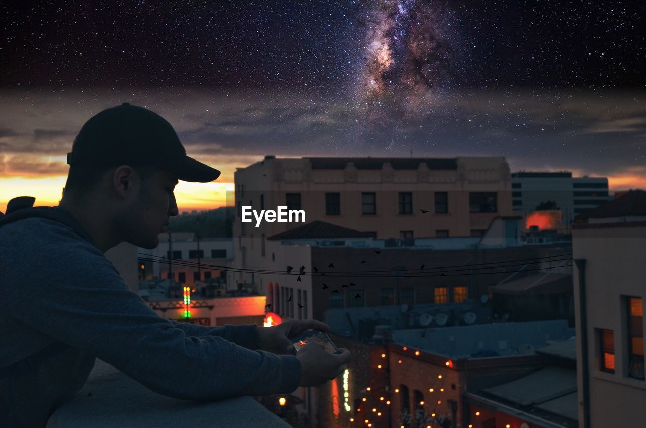 view of man using smart phone on balcony at night
