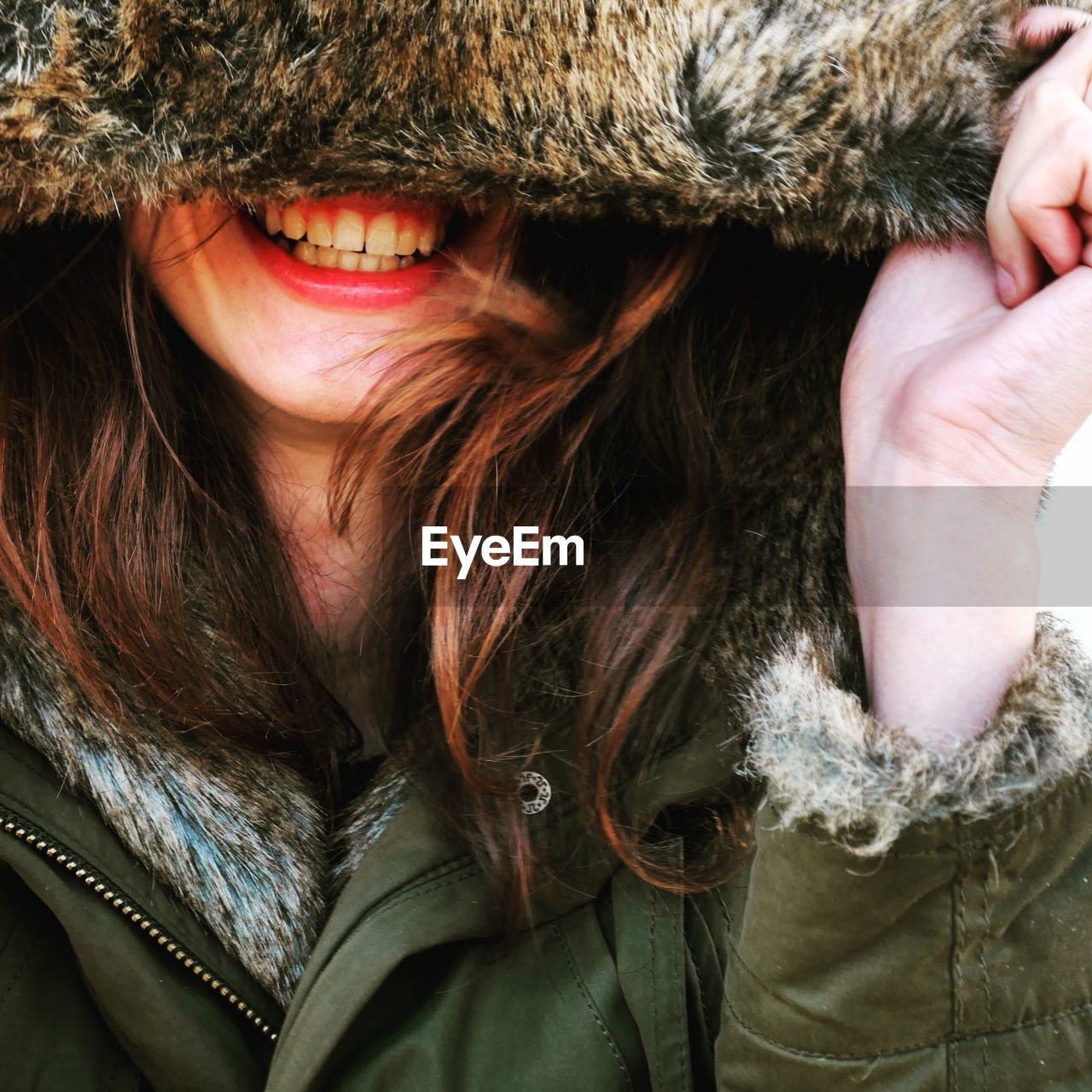 Close-up of woman laughing in hooded jacket