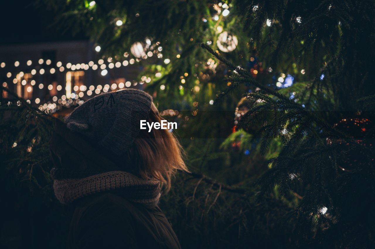 Woman looking at christmas tree at night