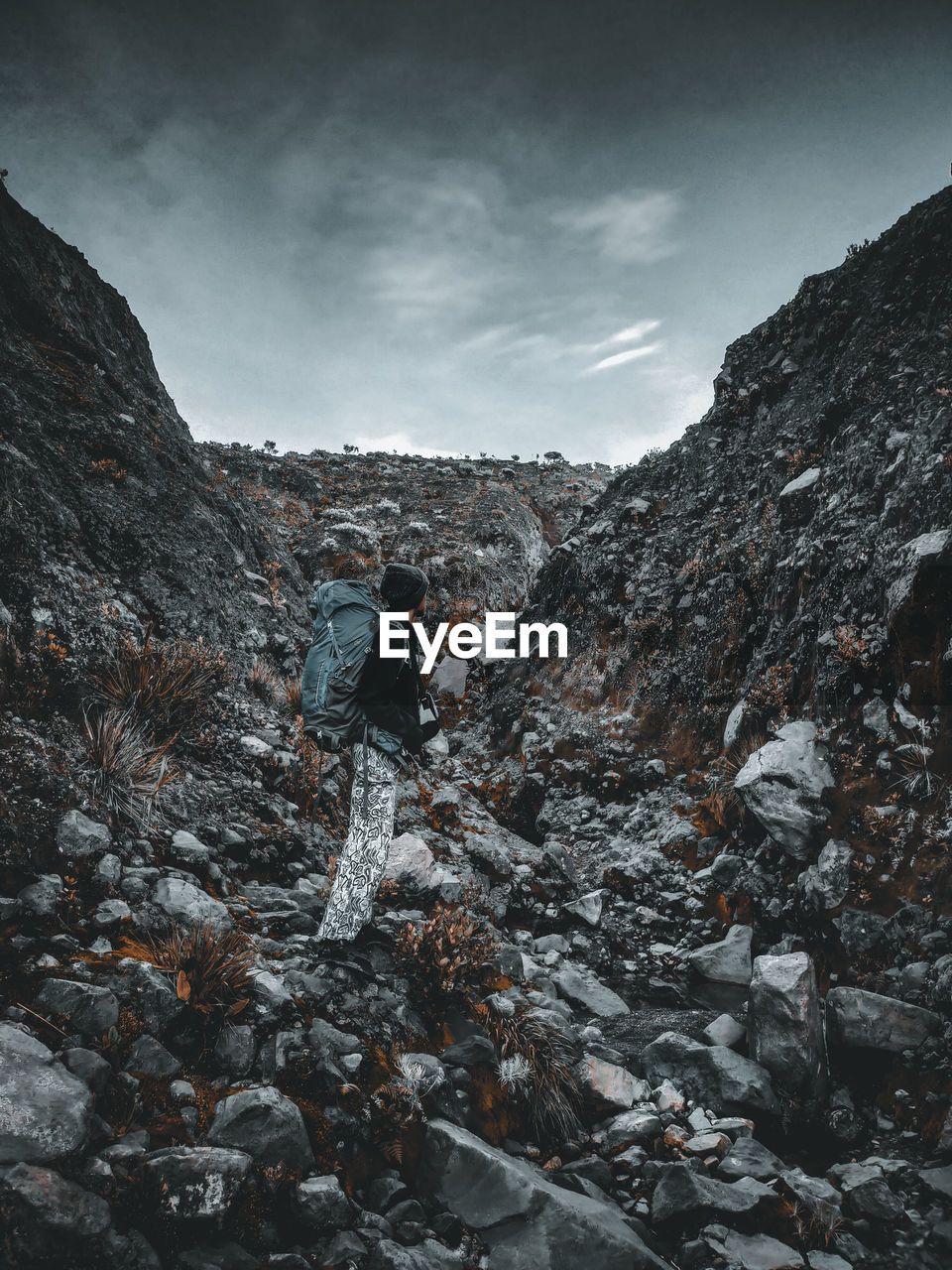 Man on rocks by mountains against sky