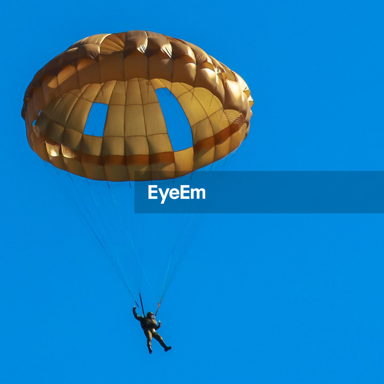 Low angle view of man paragliding against clear blue sky