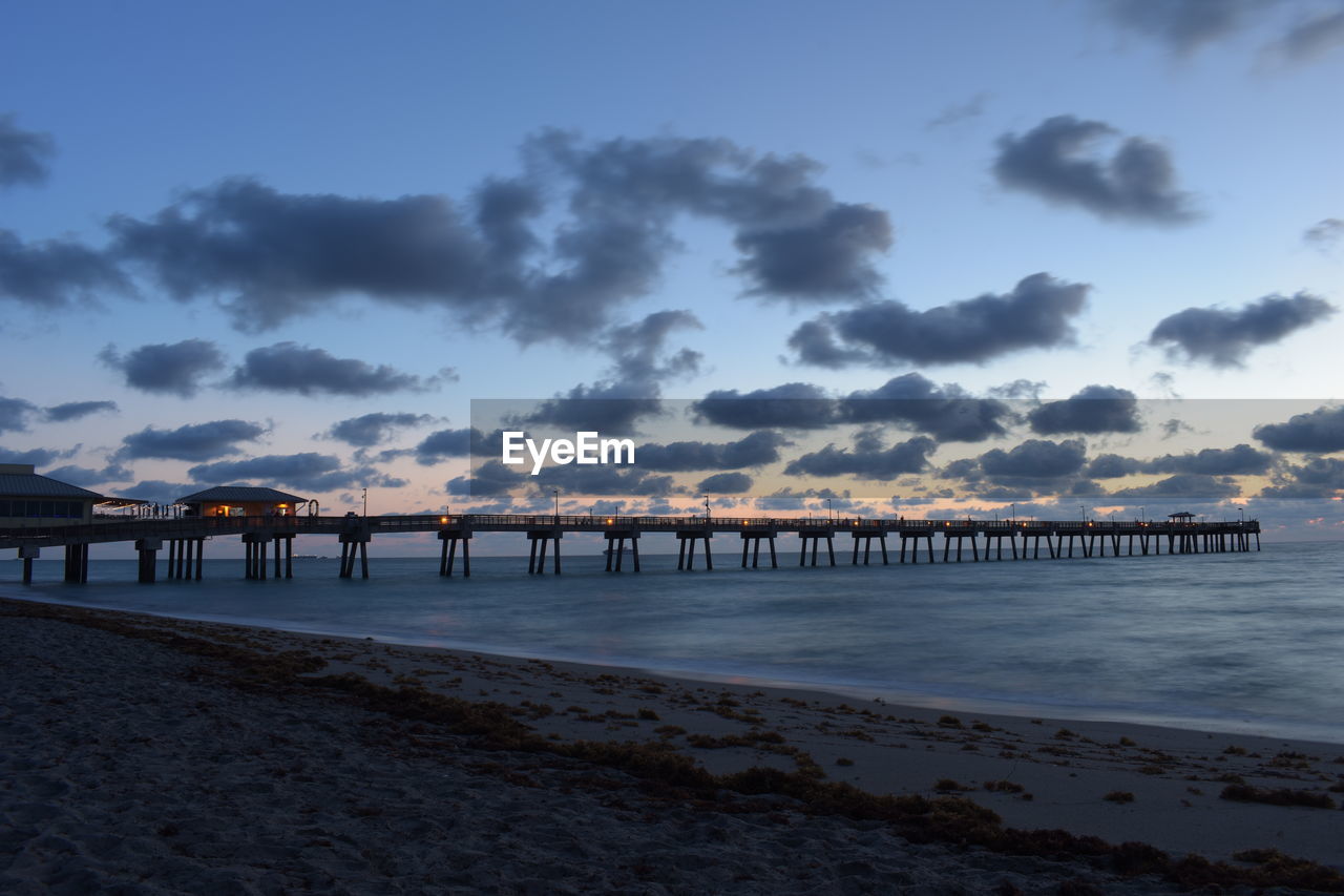 Pier over sea against sky during sunset