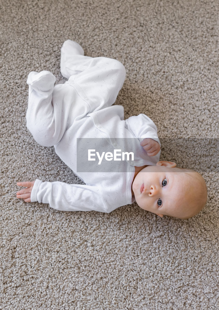 HIGH ANGLE PORTRAIT OF CUTE BOY LYING DOWN ON FLOOR