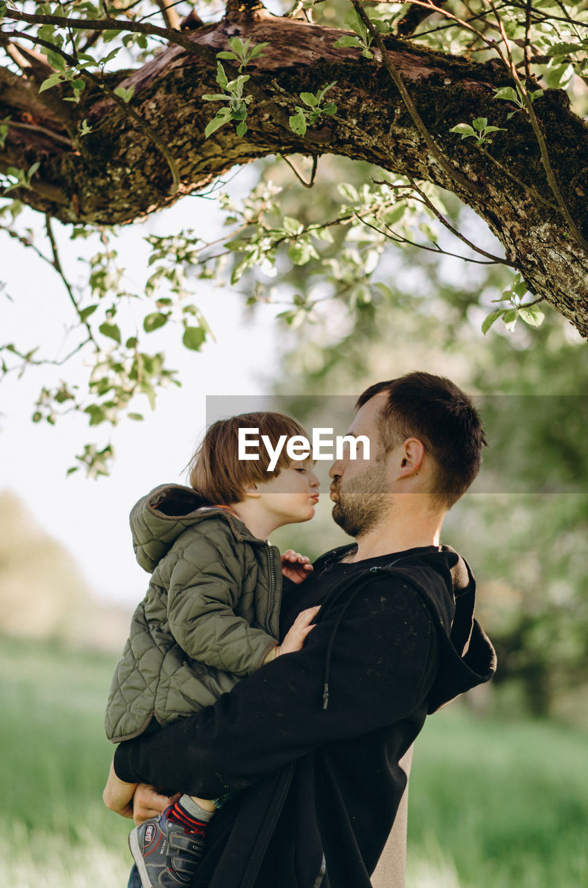 SIDE VIEW OF COUPLE STANDING ON TREE