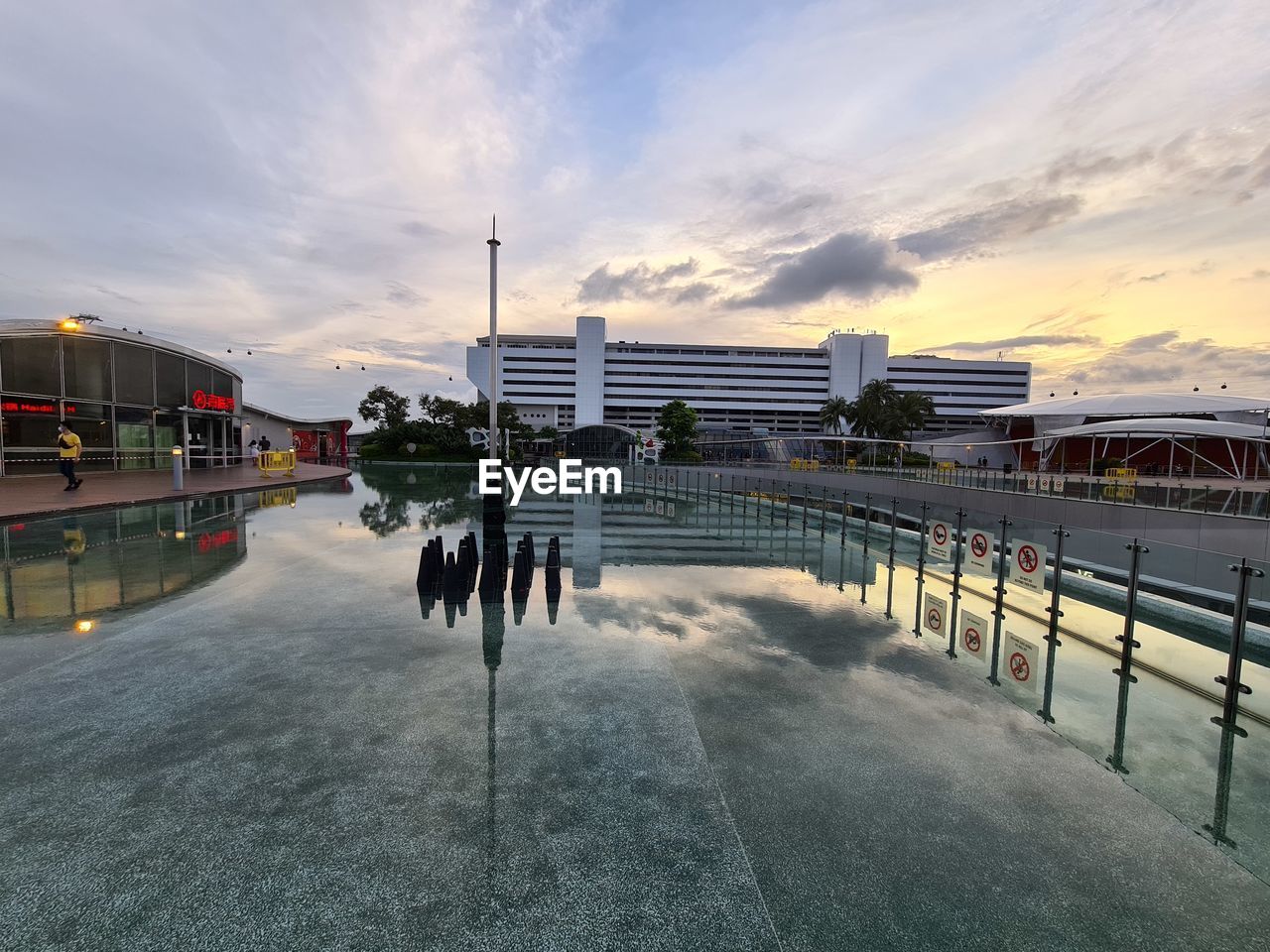 VIEW OF SWIMMING POOL AGAINST BUILDINGS AT SUNSET
