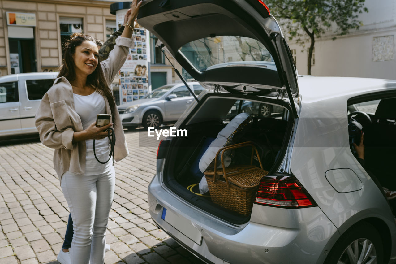 Mature woman standing by car trunk at roadside