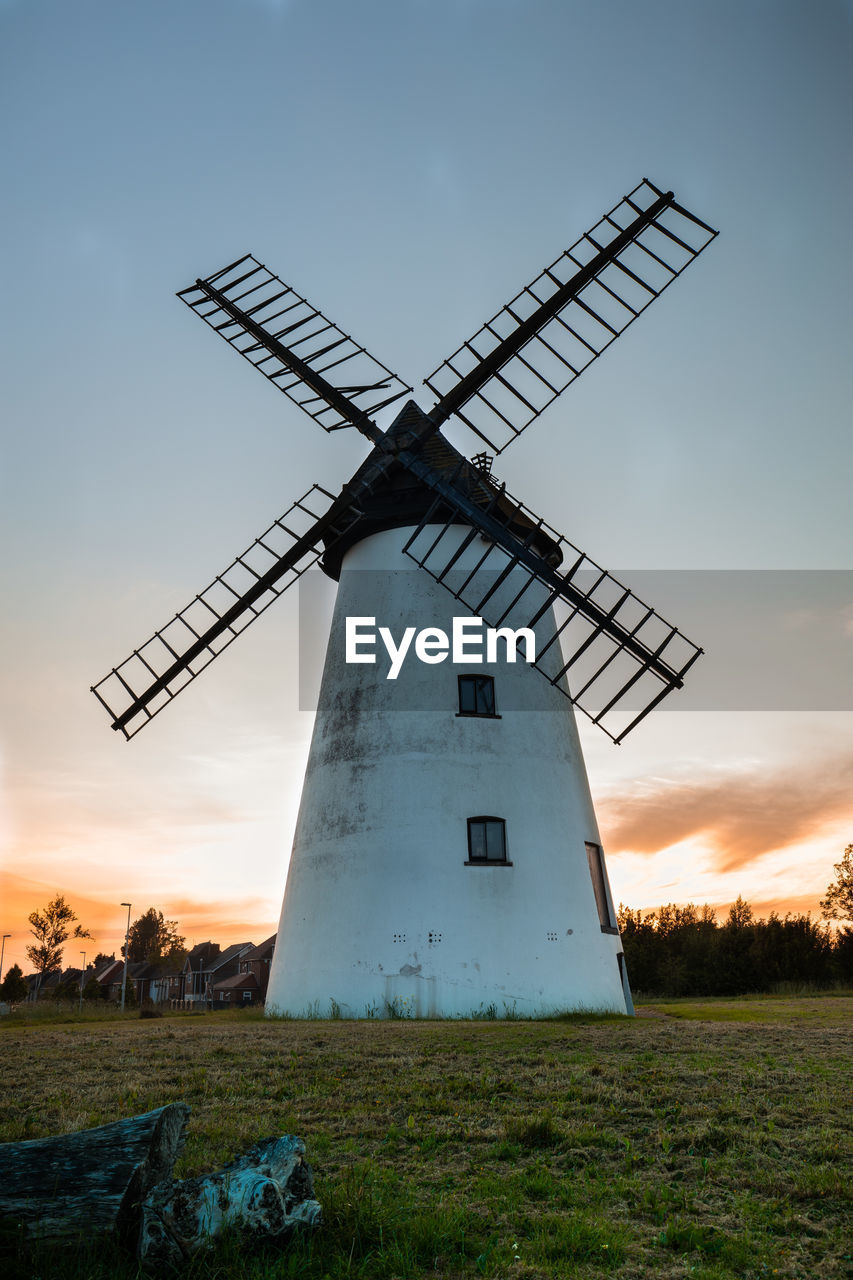 Traditional windmill on field against sky at sunset