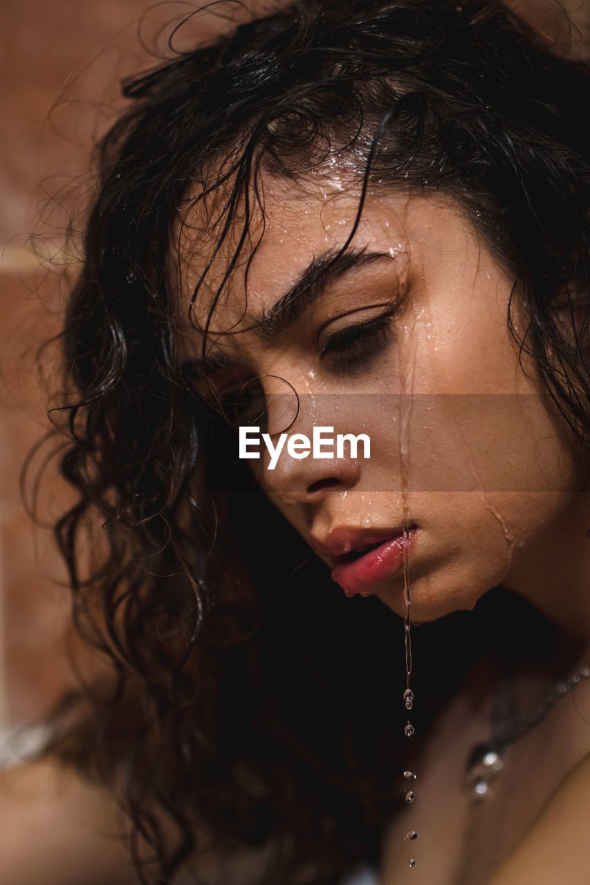 Depressive beautiful model spa woman with splashes of water on her face under the shower.