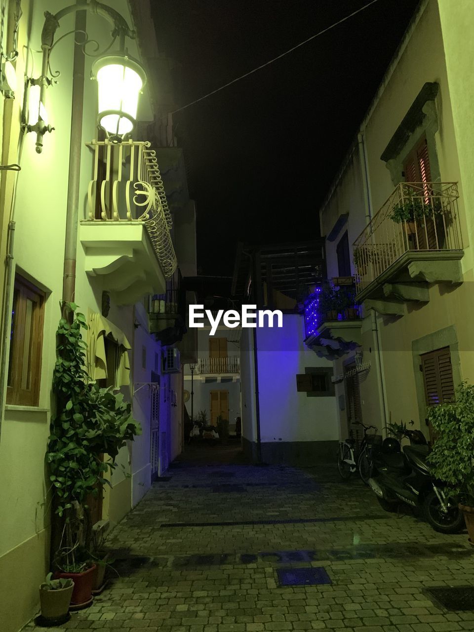 ILLUMINATED ALLEY AMIDST BUILDINGS IN CITY