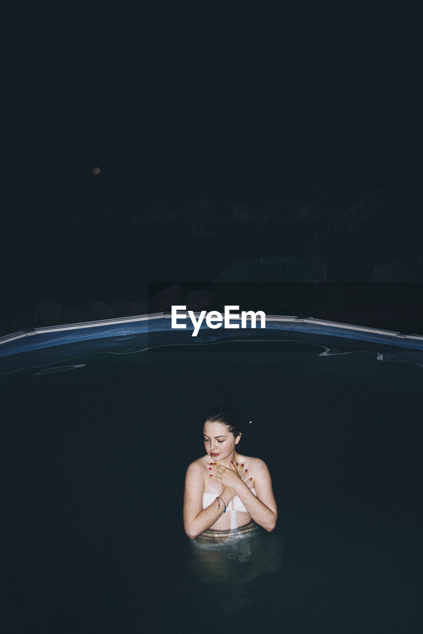 Young woman in swimming pool at night