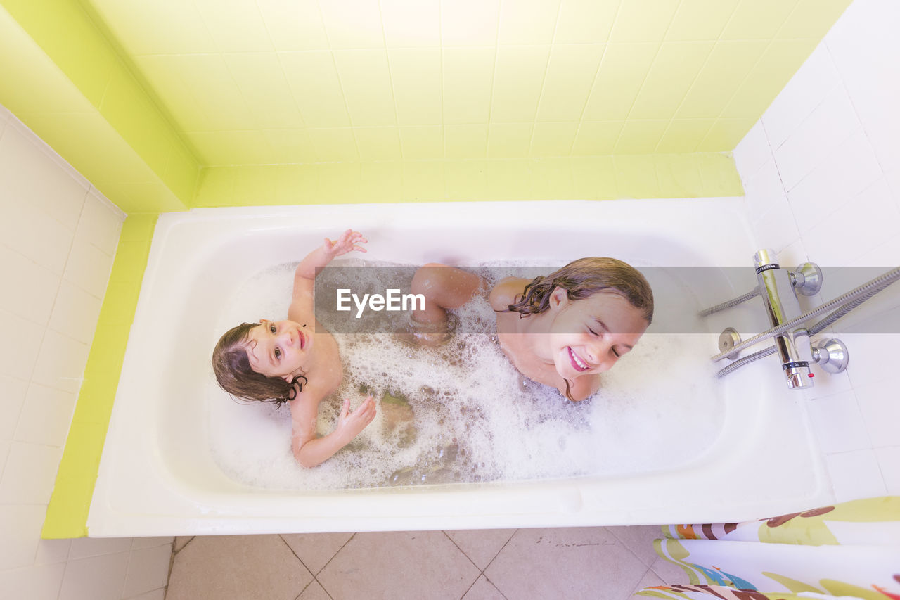 Siblings taking bath in tub at bathroom