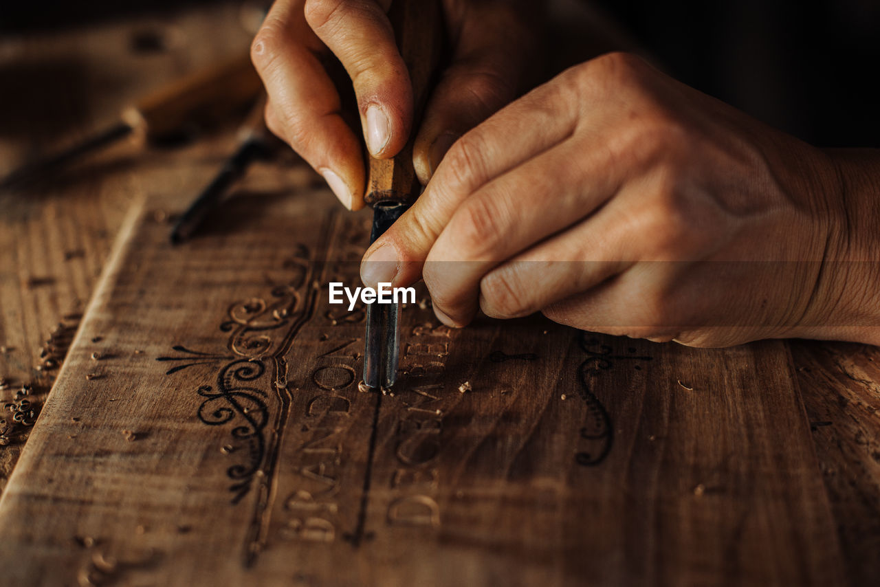 Close up process of decorative wood engraving using hand tools