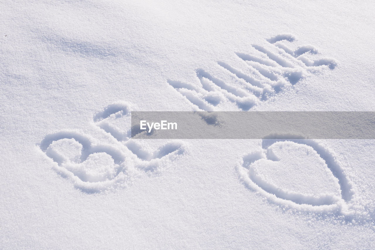 Text be mine and contour drawing in shape of heart on white snow