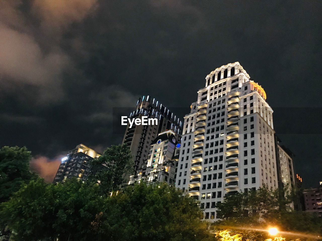 LOW ANGLE VIEW OF ILLUMINATED BUILDING AGAINST SKY AT NIGHT