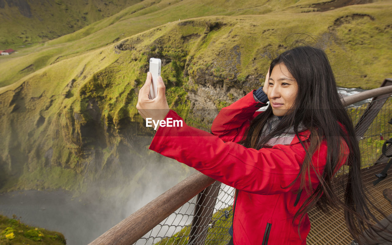 Beautiful woman taking selfie at skogarfoss waterfall in iceland