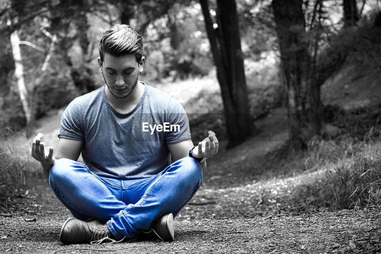 Full length of man meditating while sitting in forest