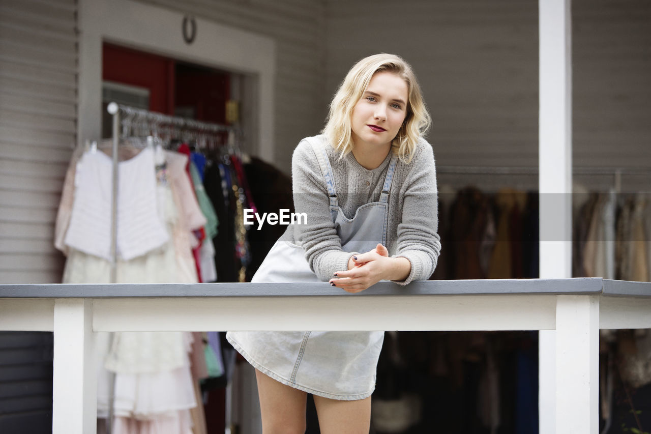 Portrait of woman leaning on railing at boutique