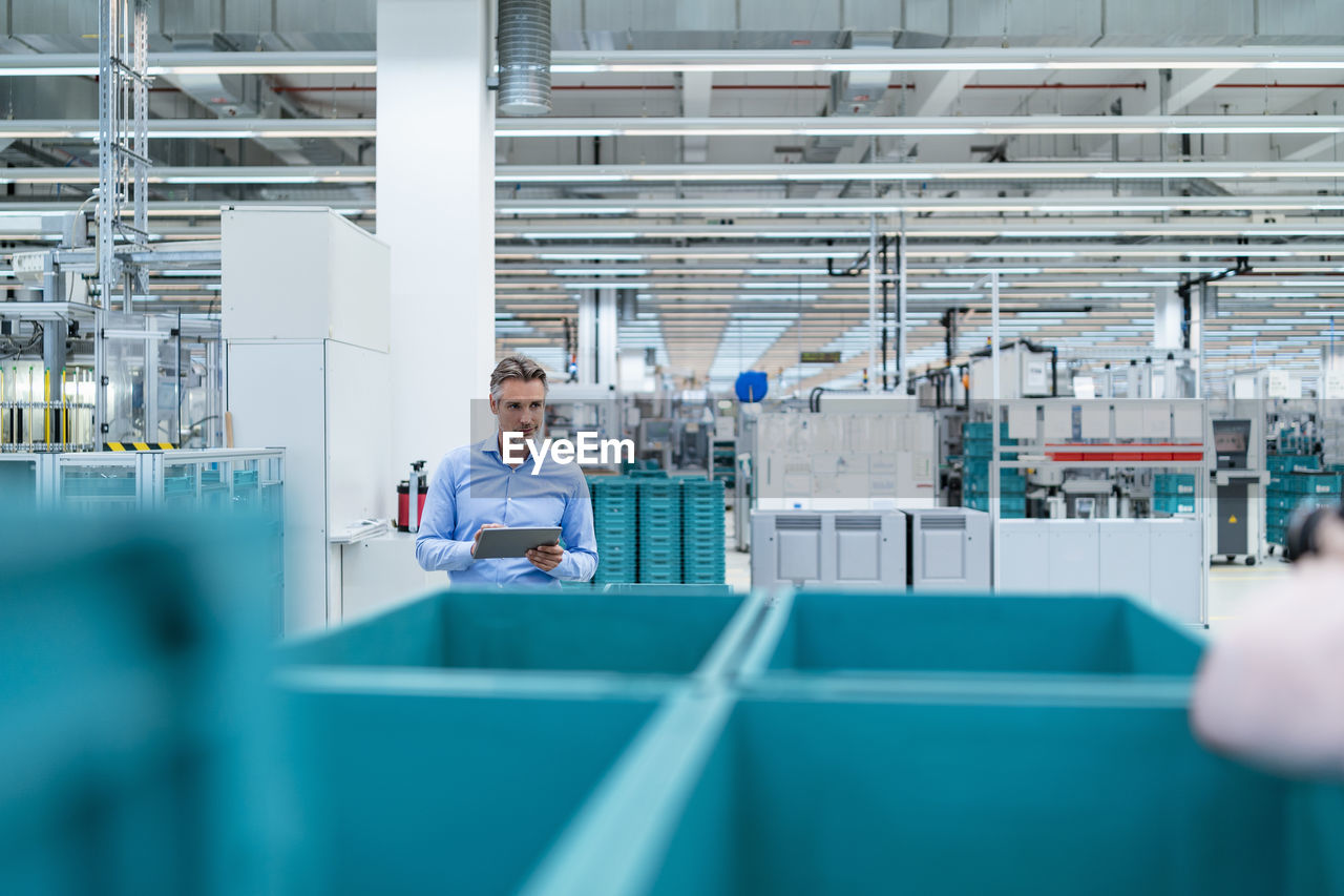 Businessman with tablet in a factory hall