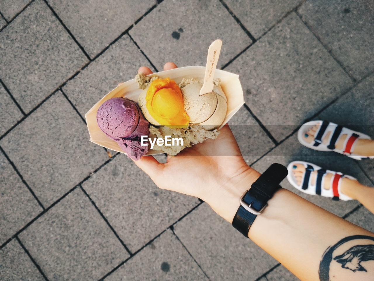 Directly above shot of woman holding ice cream on footpath