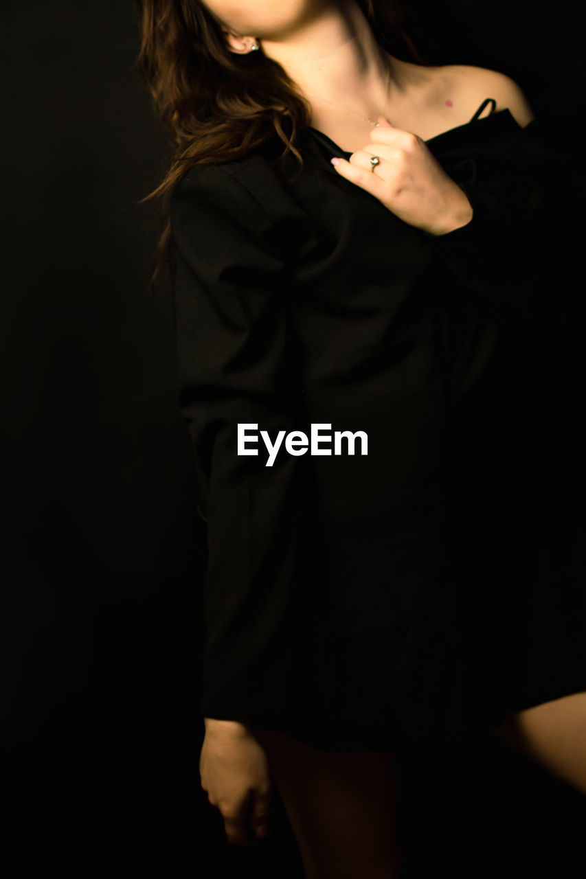 one person, women, studio shot, adult, black background, fashion, young adult, indoors, hairstyle, portrait, black, long hair, three quarter length, clothing, dress, elegance, brown hair, dark, glamour, standing, front view, person, looking at camera, female, photo shoot, darkness, formal wear, copy space