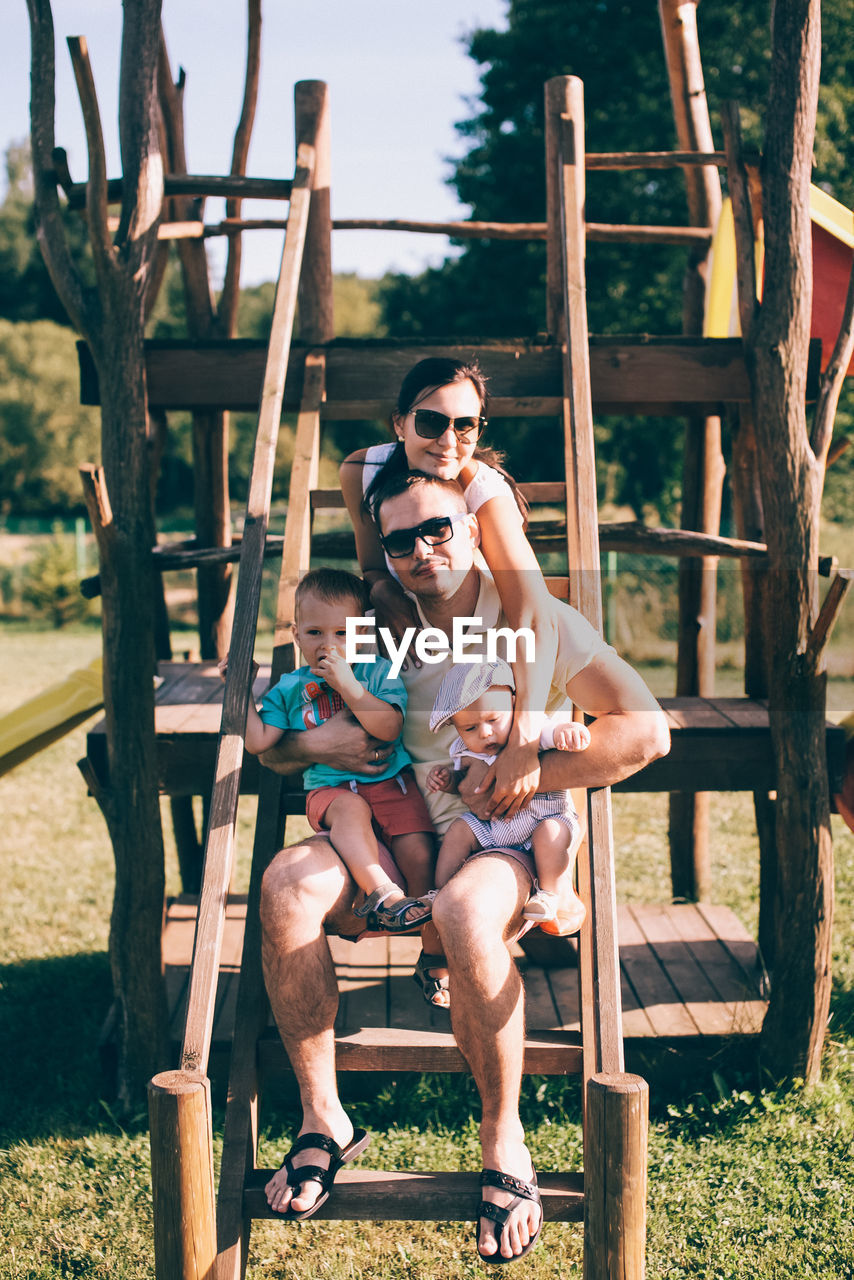 PORTRAIT OF FRIENDS SITTING ON PLAYGROUND