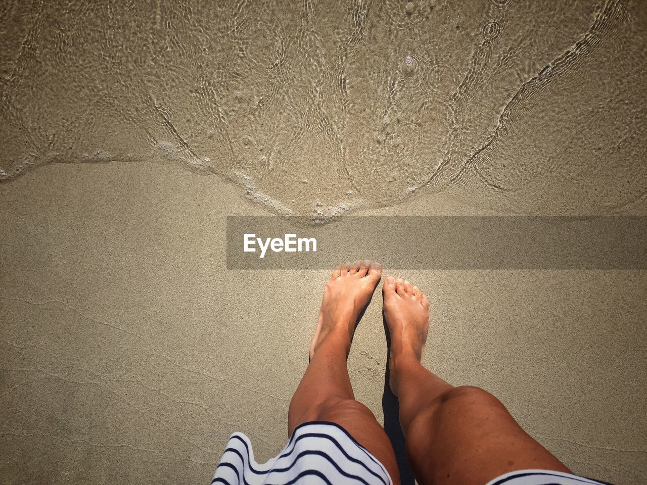 Low section of woman standing at beach