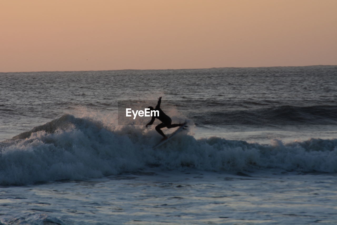 MAN SURFING IN SEA AGAINST SKY