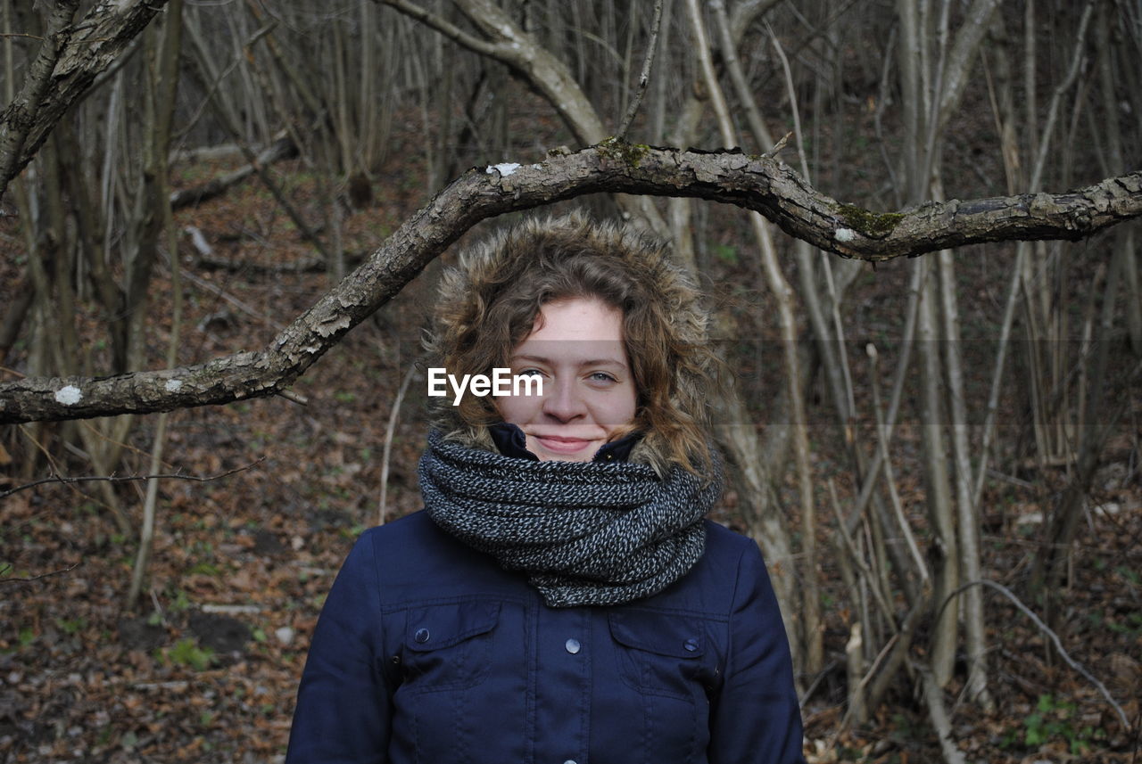 Portrait of smiling young woman standing at forest