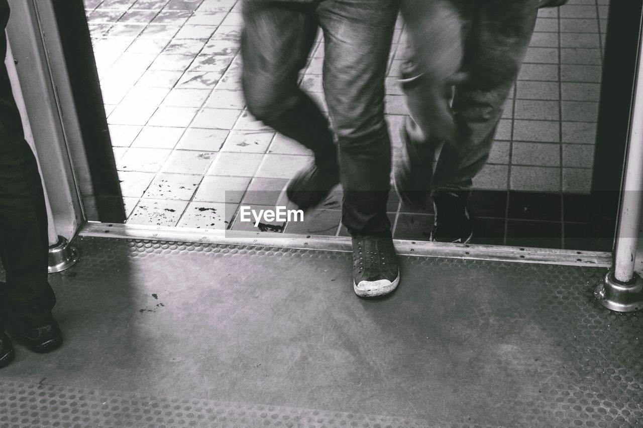 LOW SECTION OF PERSON STANDING ON TILED FLOOR