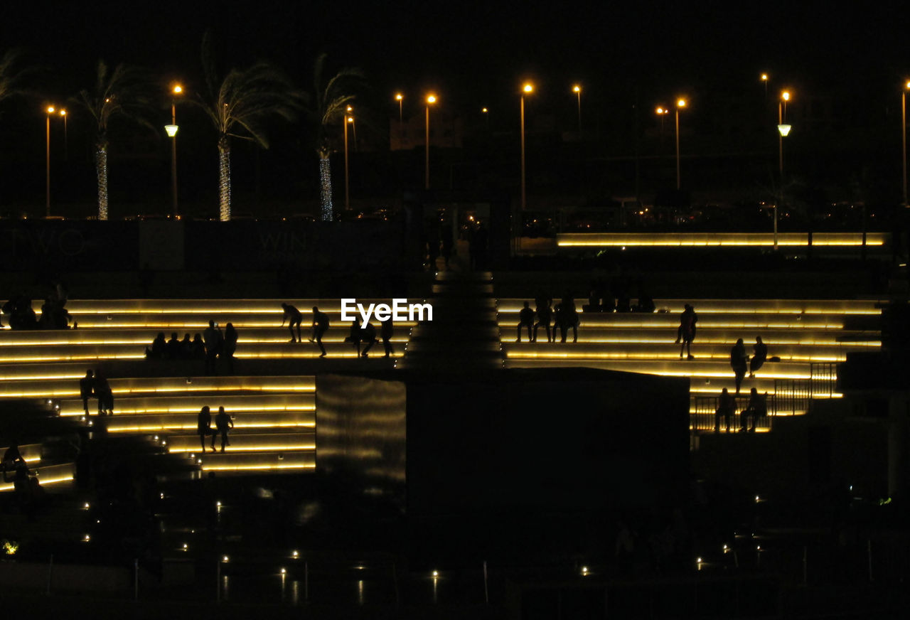 Silhouettes of people sitting on illuminating steps. cairo festival city amphitheater