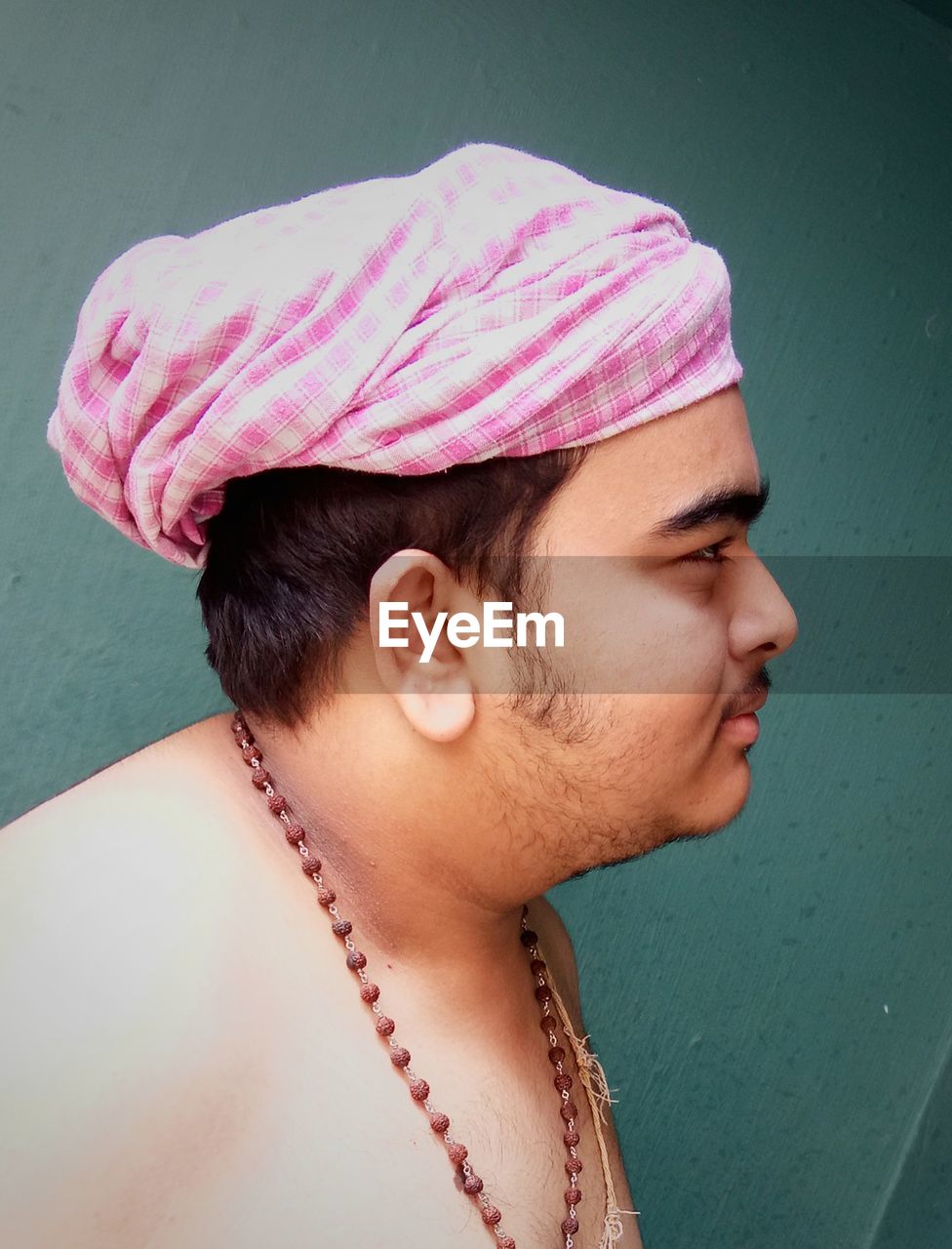 Close-up of shirtless man in headwear at home