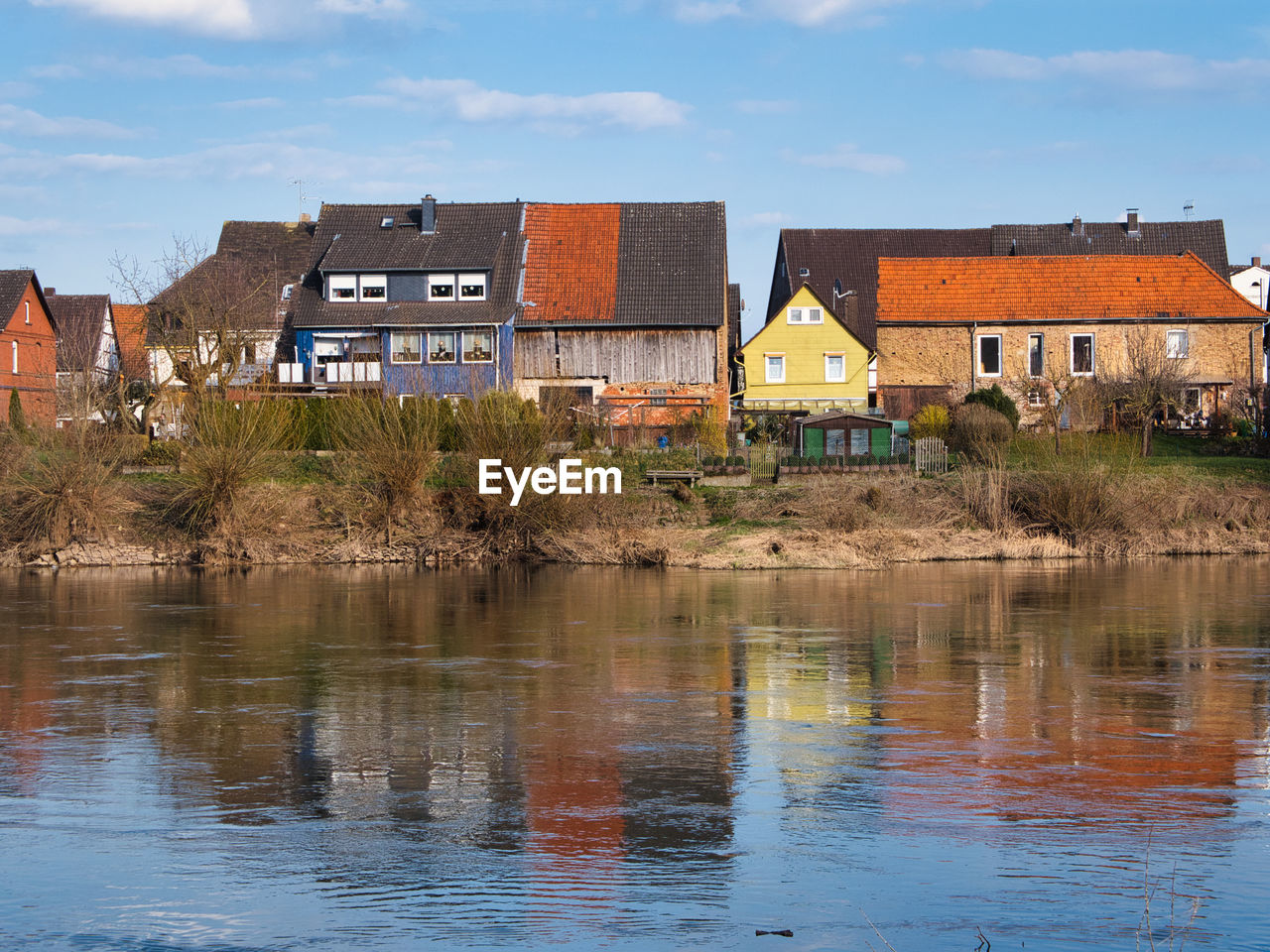 Buildings by river against sky