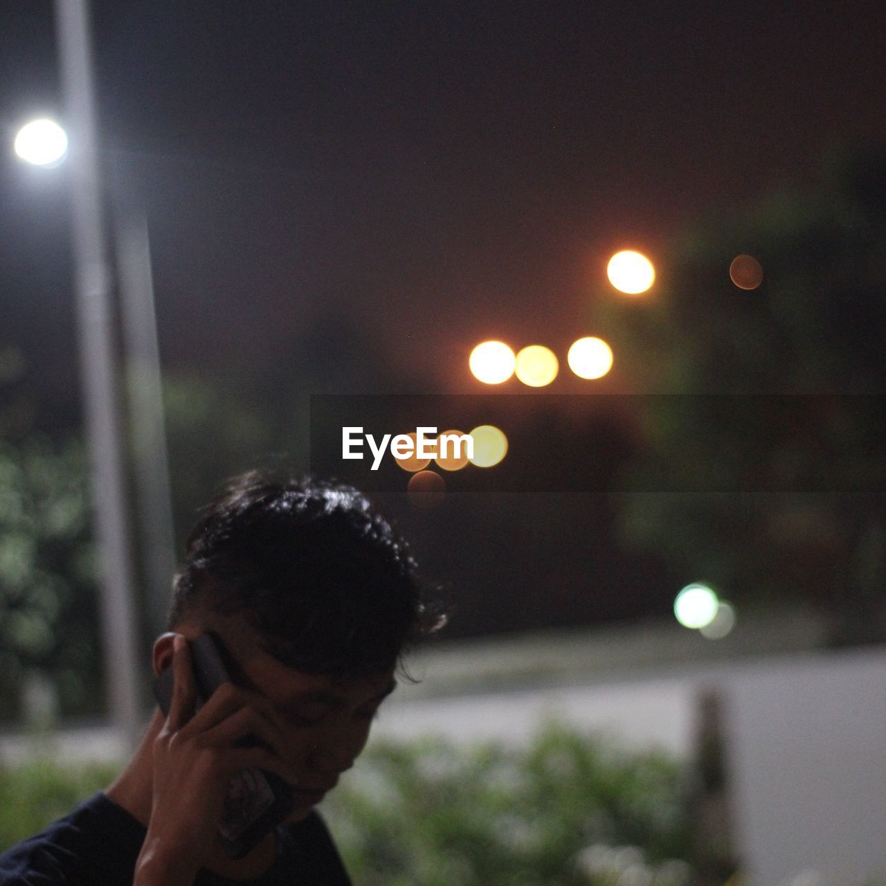 PORTRAIT OF YOUNG MAN LOOKING AT ILLUMINATED STREET