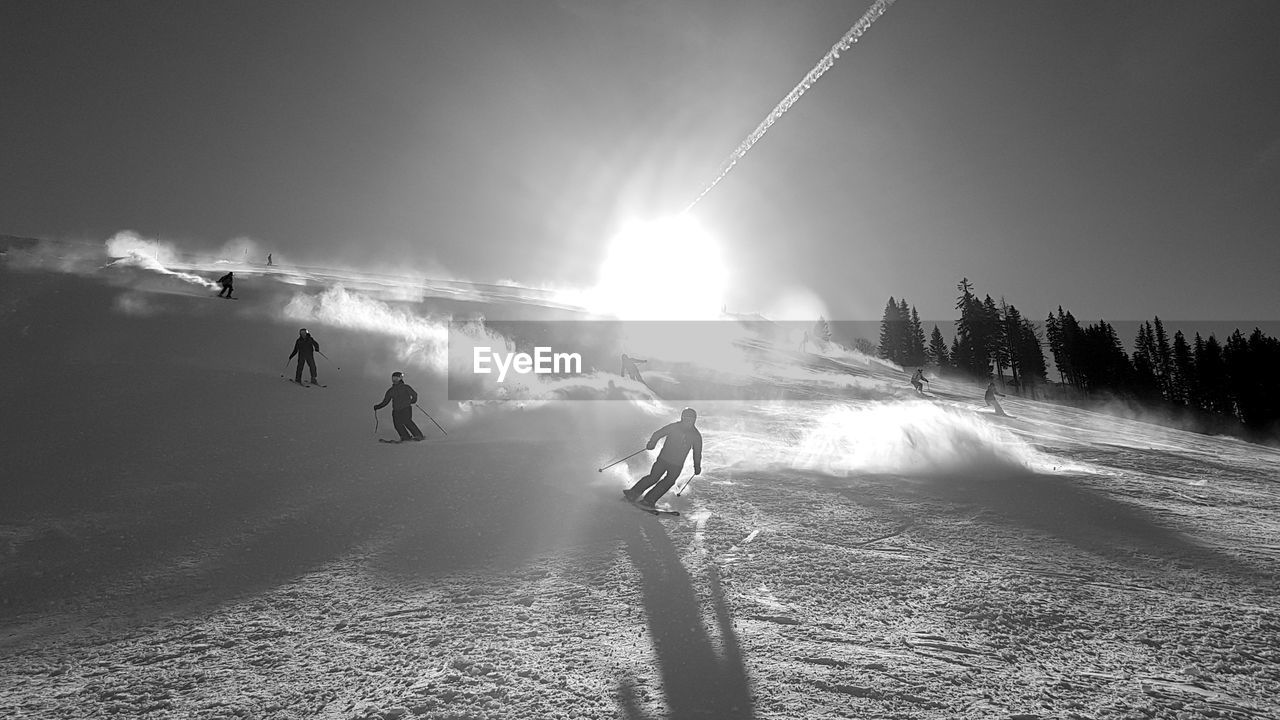 PEOPLE SKIING ON FIELD AGAINST SKY