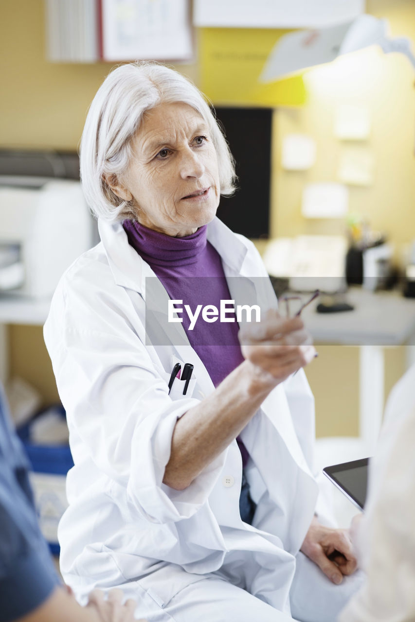 Senior female doctor having serious discussion with colleagues in hospital