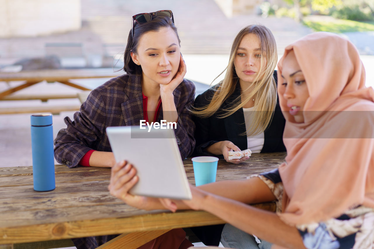 Female friends looking at digital tablet in cafe